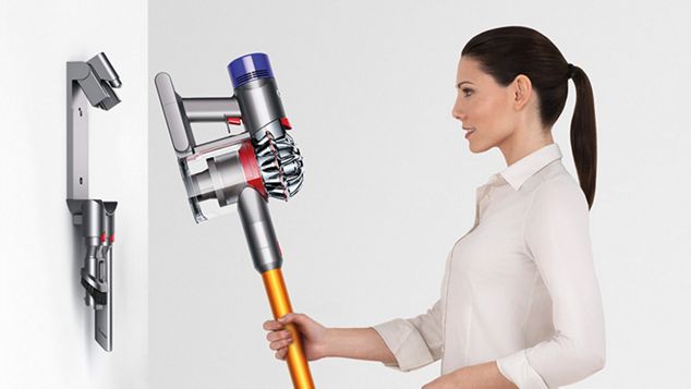 Žena umisťující vysavač Dyson V8 zpět do dobíjecí stanice